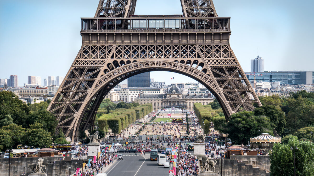 The legs of Eiffel Tower with tourist crowd waiting in lines