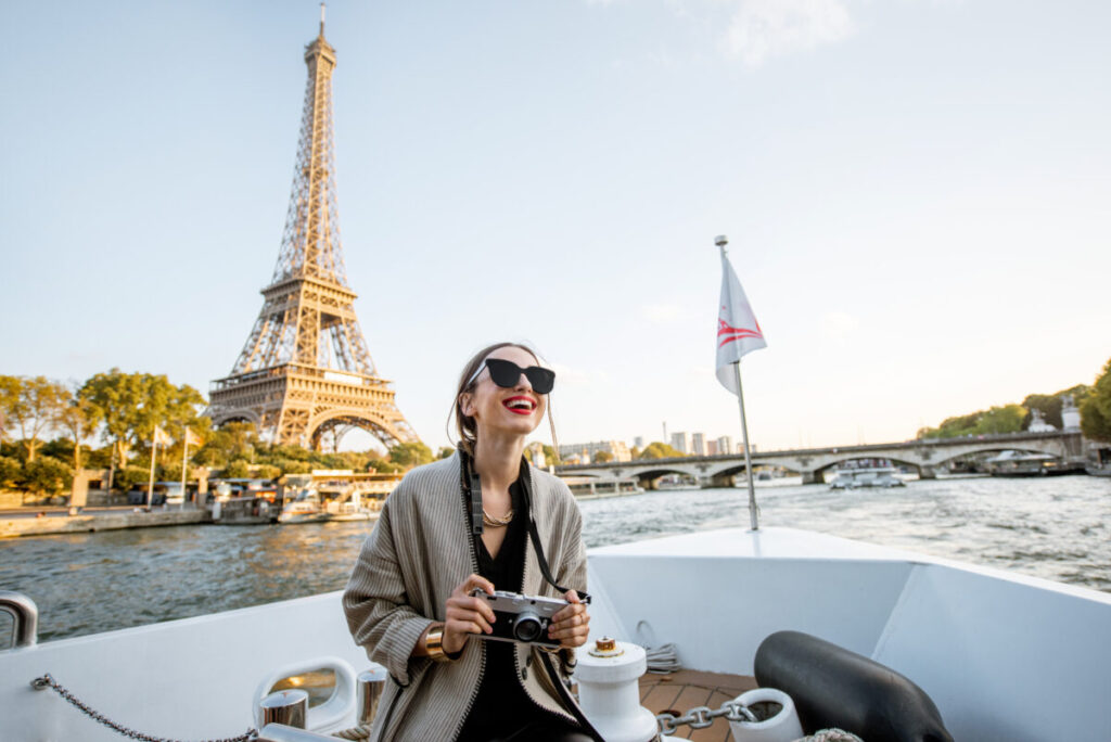 Young woman enjoying beautiful landscape view on the riverside with Eiffel tower from the boat during the sunset in Paris