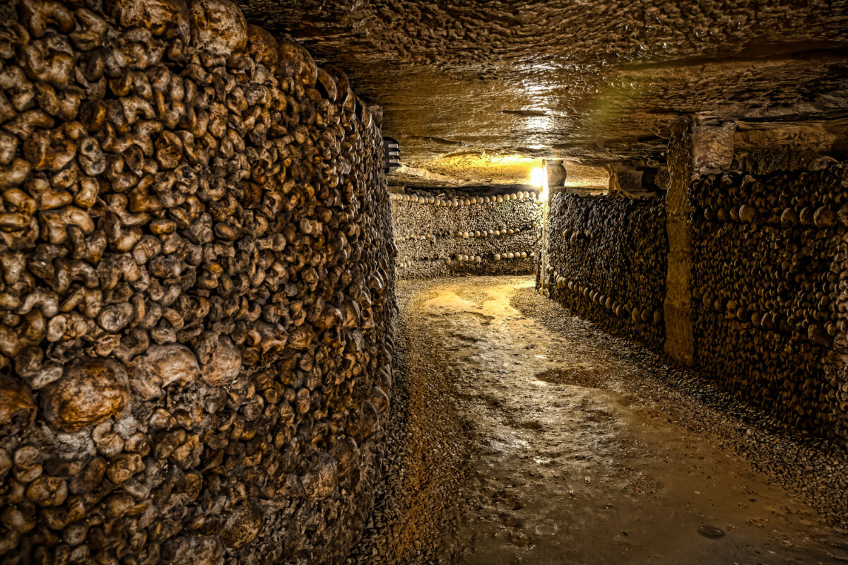 Paris Catacombs corridor with arranged skulls and bones, eerie and historical.