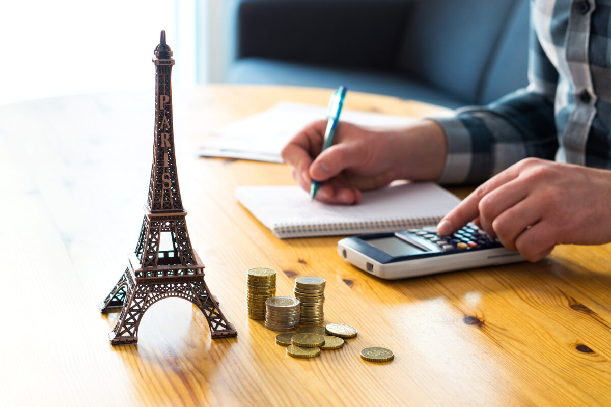 Planning Paris vacation budget with Eiffel Tower model and finances on table.