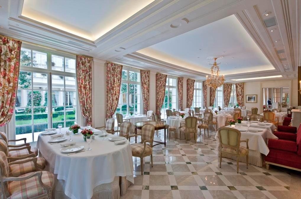 The dining room exudes opulence, with rich fabric, sparkling chandeliers, and tasteful artwork adorning the walls.