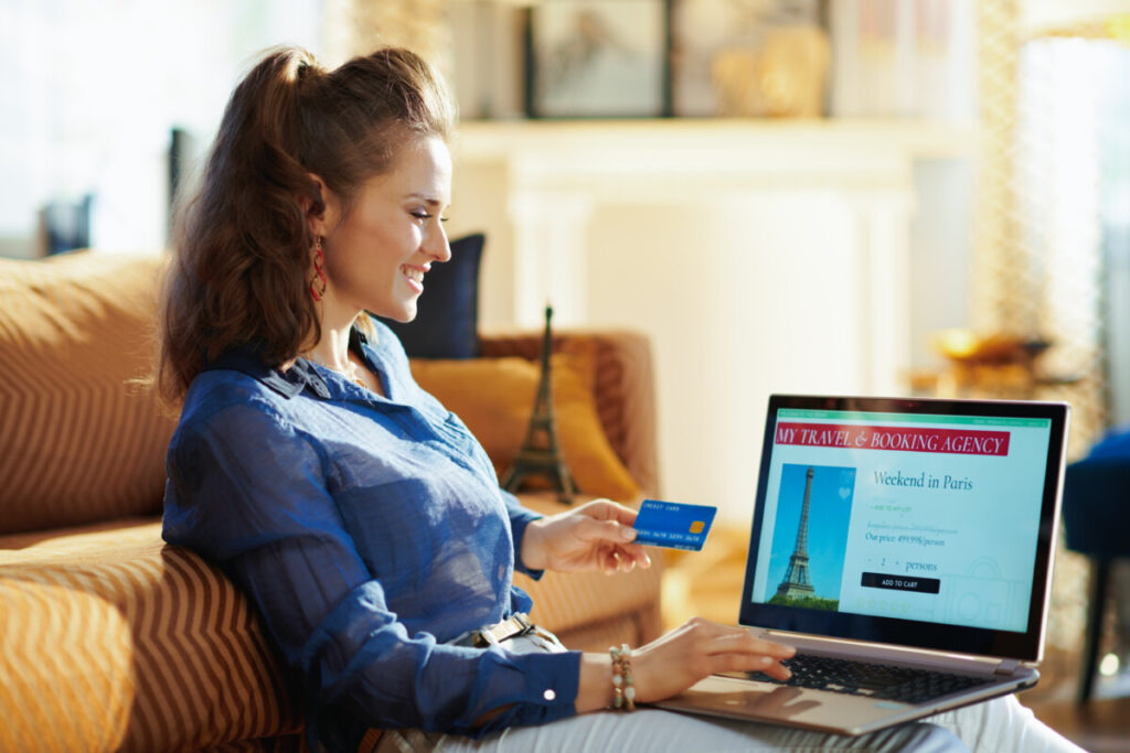 woman with online travel site on laptop holding blue credit card