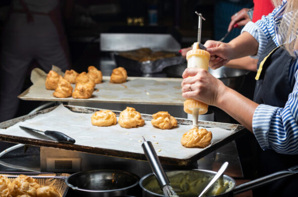 Woman using a confectionery syringe in a French pastry eclairs cooking and baking class