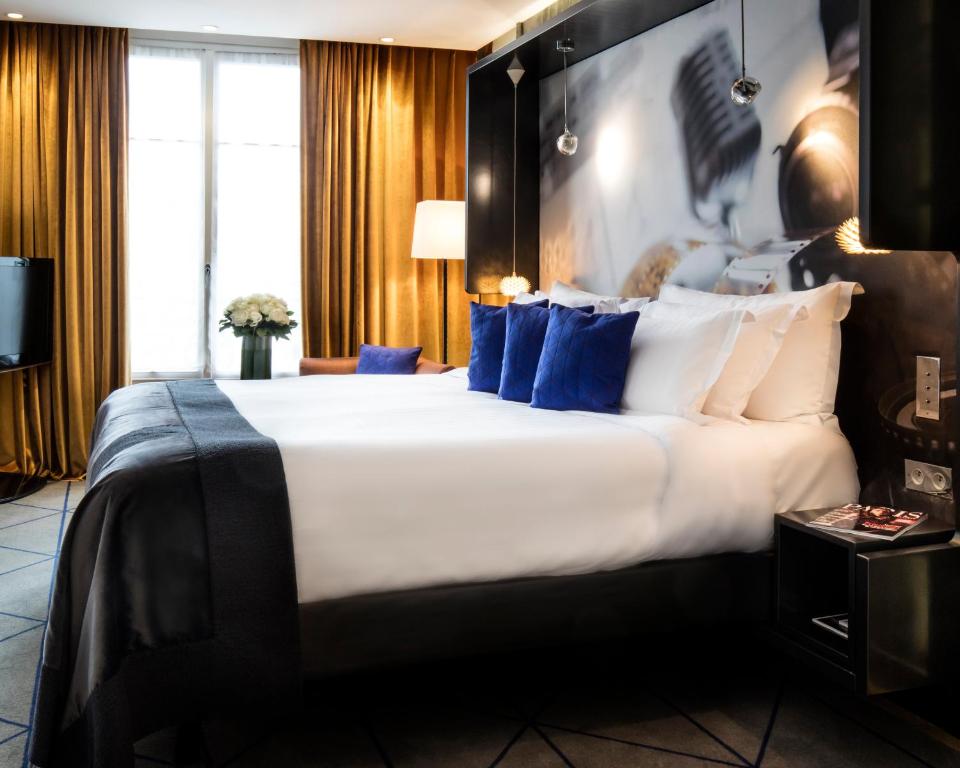 Luxurious hotel room at Hôtel De Sers Champs Elysées Paris, featuring elegant furnishings, plush bedding, and large windows with views of Paris.