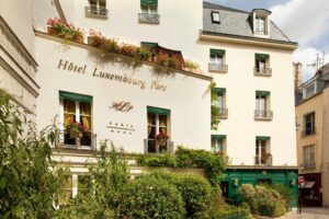 The elegant facade of Hotel Luxembourg Parc, showcasing classic Parisian architecture with ornate details, tall windows, and wrought iron balconies.