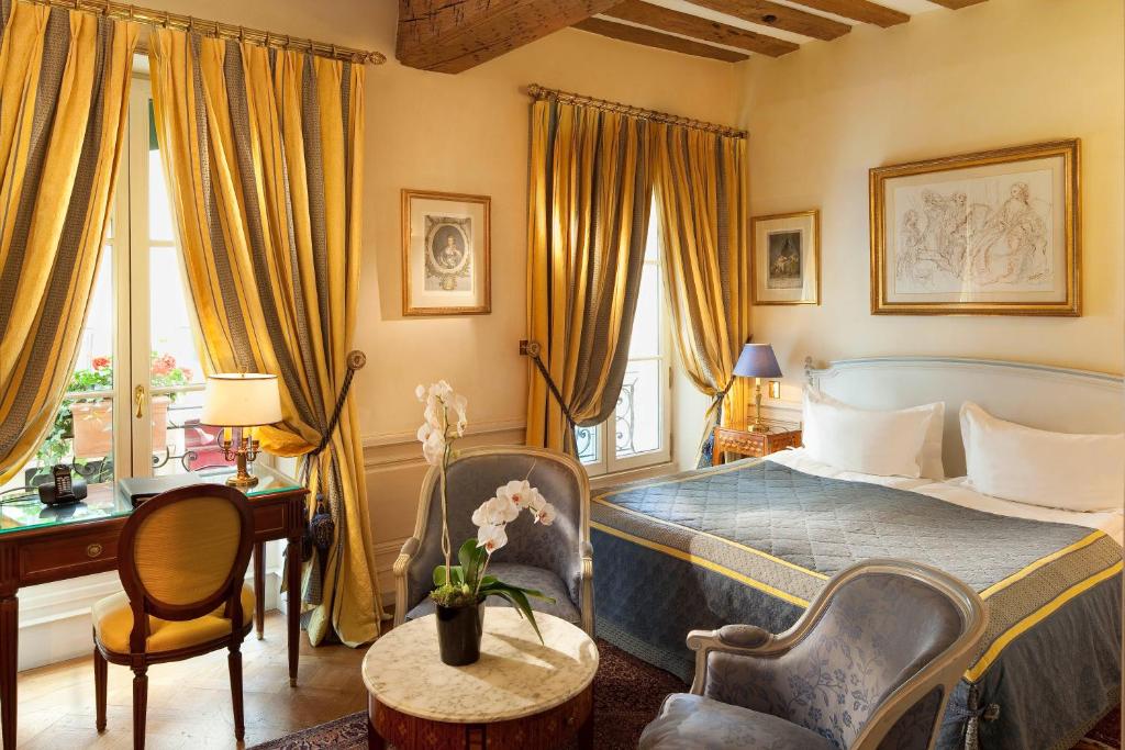 A luxurious hotel room at Hotel Luxembourg Parc, featuring elegant furnishings, a plush bed with fine linens, and large windows offering views of the surrounding gardens.