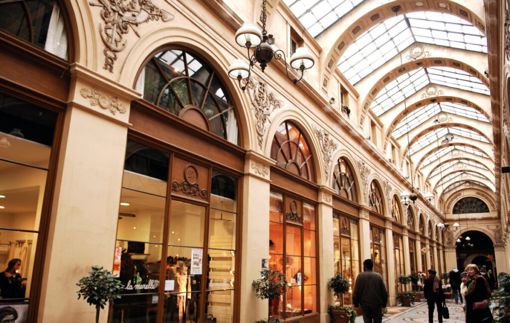 The stunning interior of Galerie Vivienne in Paris, featuring intricate design elements and a lively shopping environment