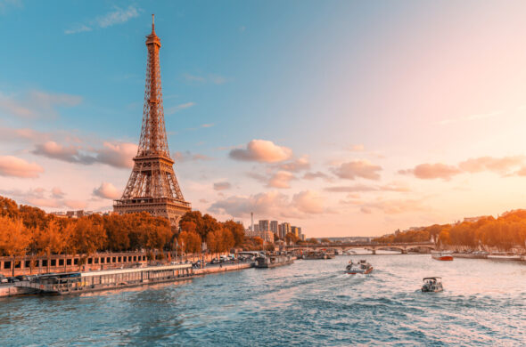 Panoramic sunset over the Eiffel Tower and Seine River with a passing cruise boat