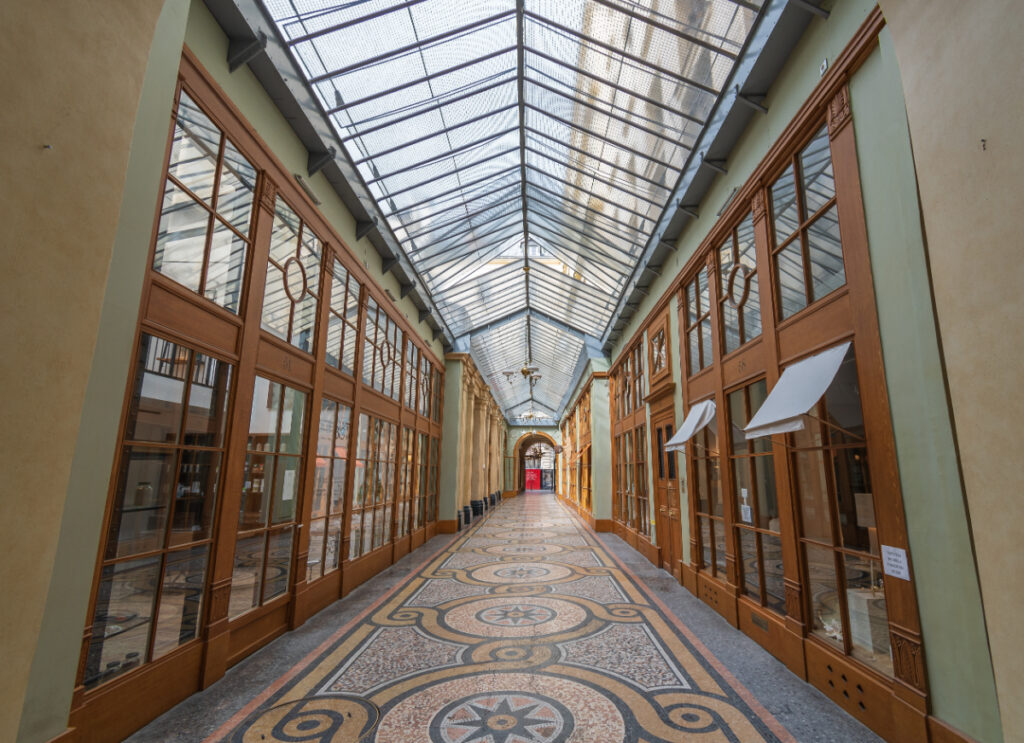 Interior view of Galerie Vivienne showcasing elegant architecture and vibrant shops under a glass canopy