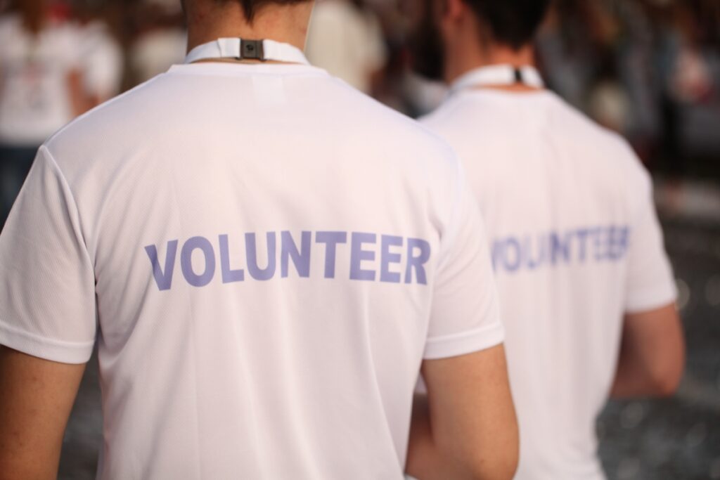 Men wearing T-shirts that read "Volunteers" at a community event